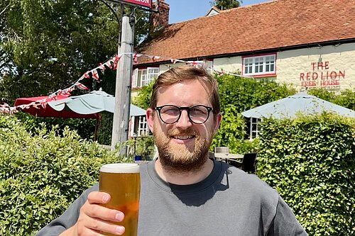Freddie holding a pint outside a pub