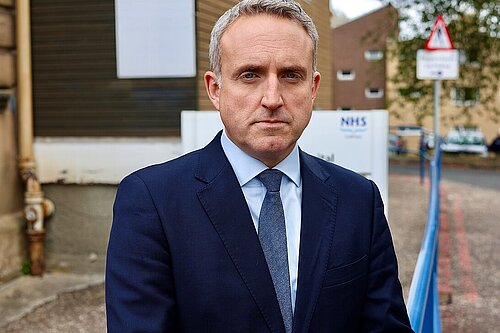 Alex Cole Hamilton standing in front of an NHS sign
