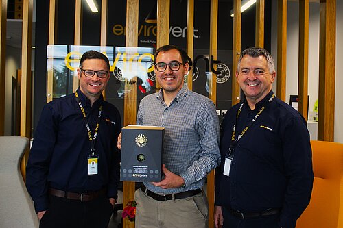 Tom Gordon MP, stood in the EnviroVent building, holding their 3 millionth fan with two employees 