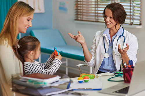 A mother holding a child whilst a GP speaks to them