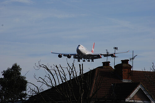 A plane flying close to houses.