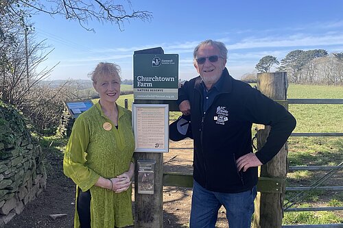 Cornwall Councillor Hilary Frank with Bob Austin, standing by a sign that says Churchtown Farm
