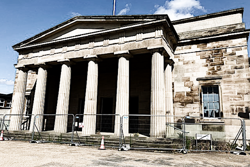 Photo of the frint of the Shirehall with builders fencing