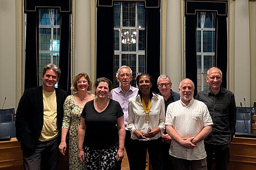 A photo of 8 people in an ornate room