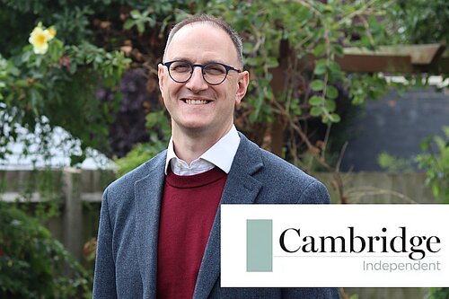 Ian Sollom MP in front of bushes and trees, with the Cambridge Independent logo emblazoned on the bottom right